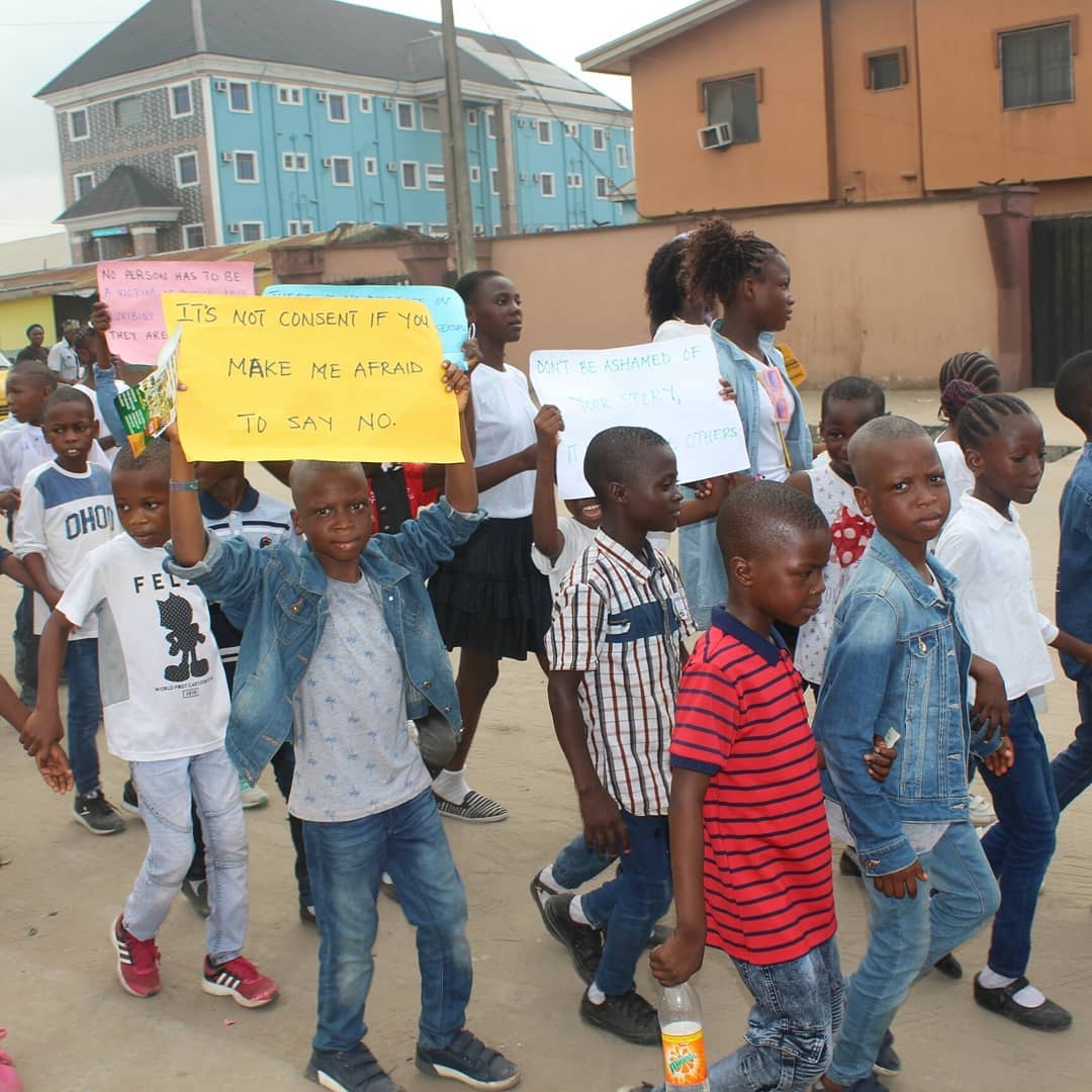 Children marching in an OLIC awareness rally holding placards
