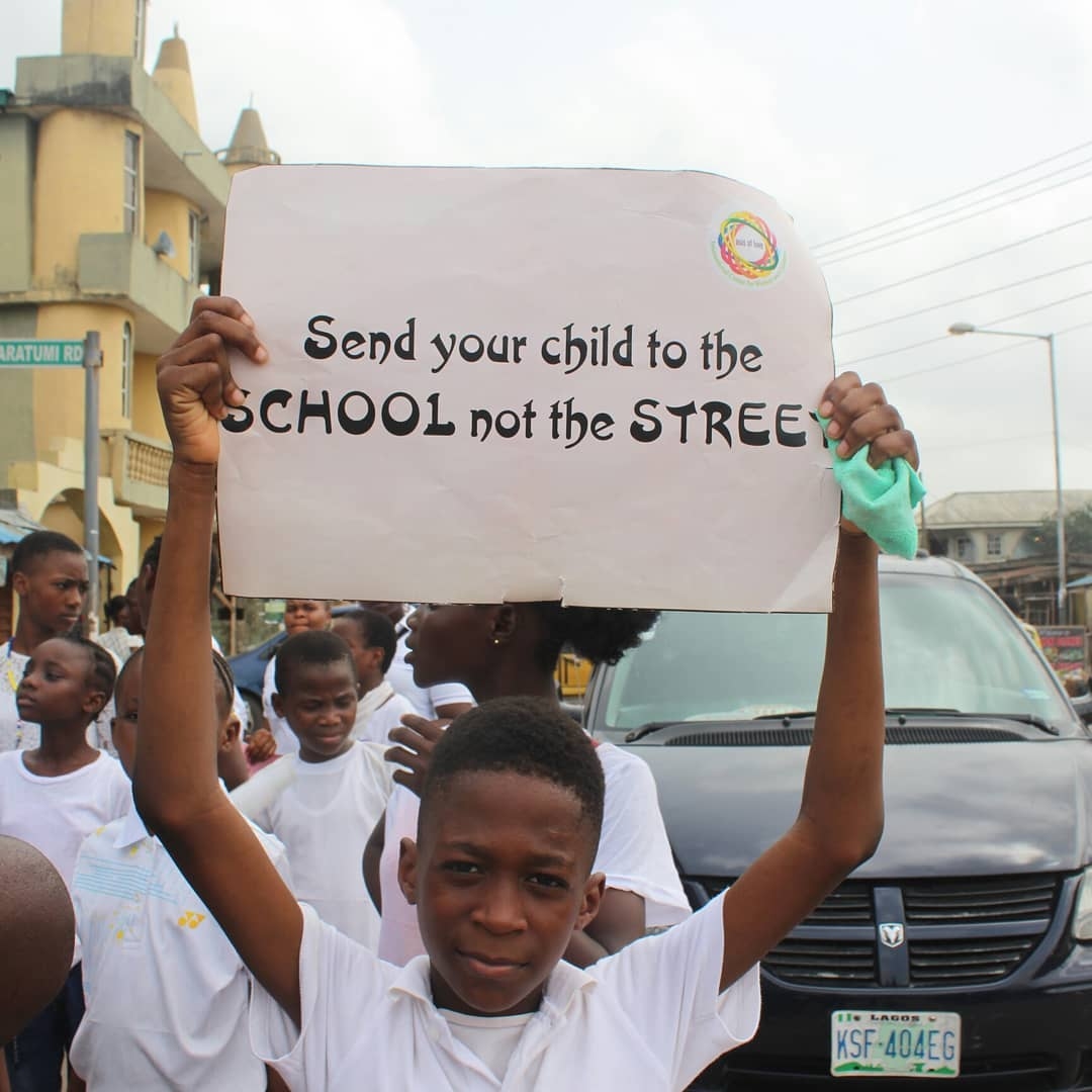 Schoolboy holding a placard: Send your child to the school, not the street