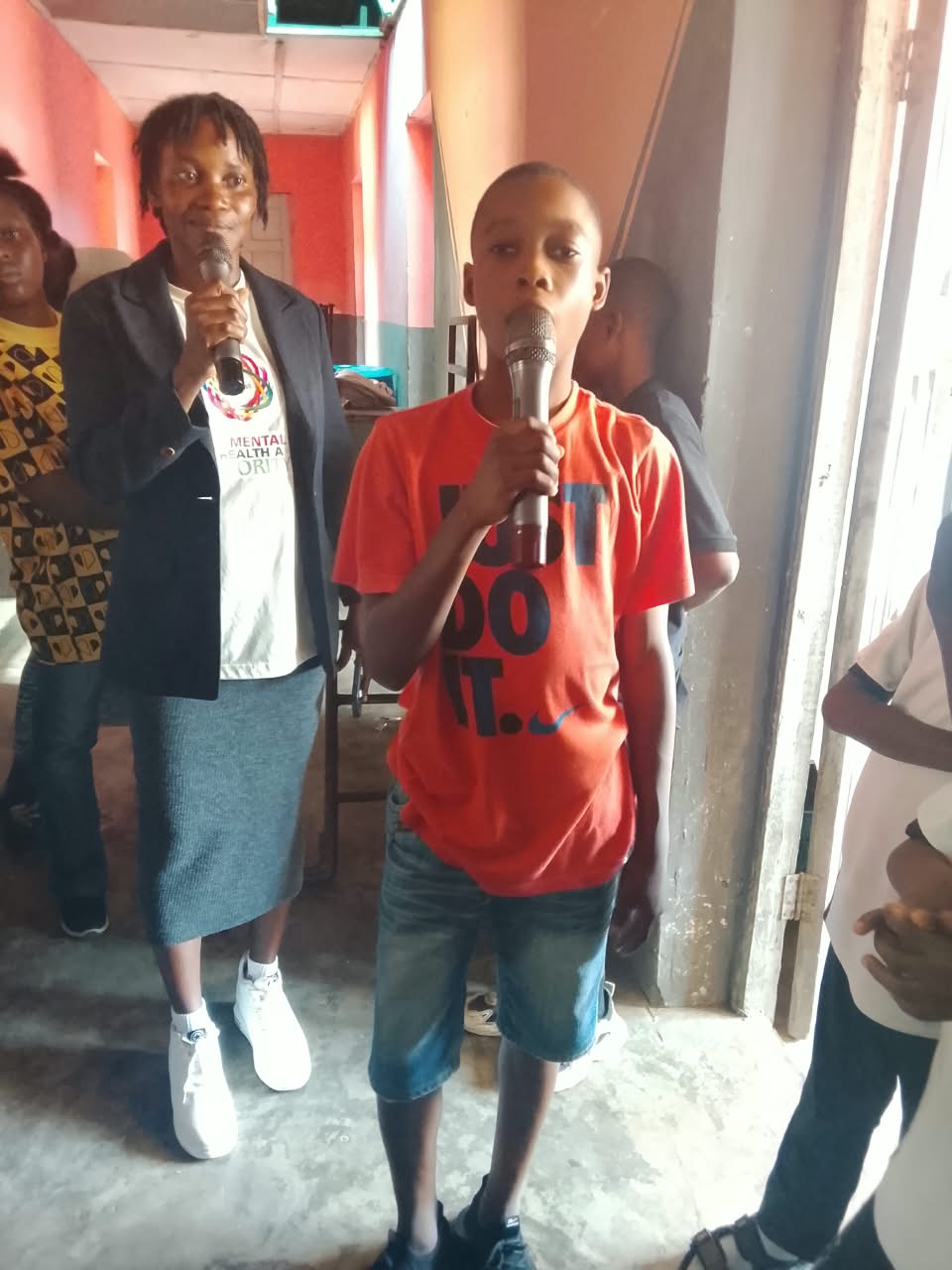 Presenter Margareth Oluwatomiwa holding a microphone beside a pupil who is also speaking into a microphone during the seminar